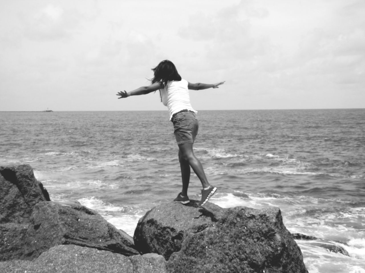 Young woman standing on rock against sea