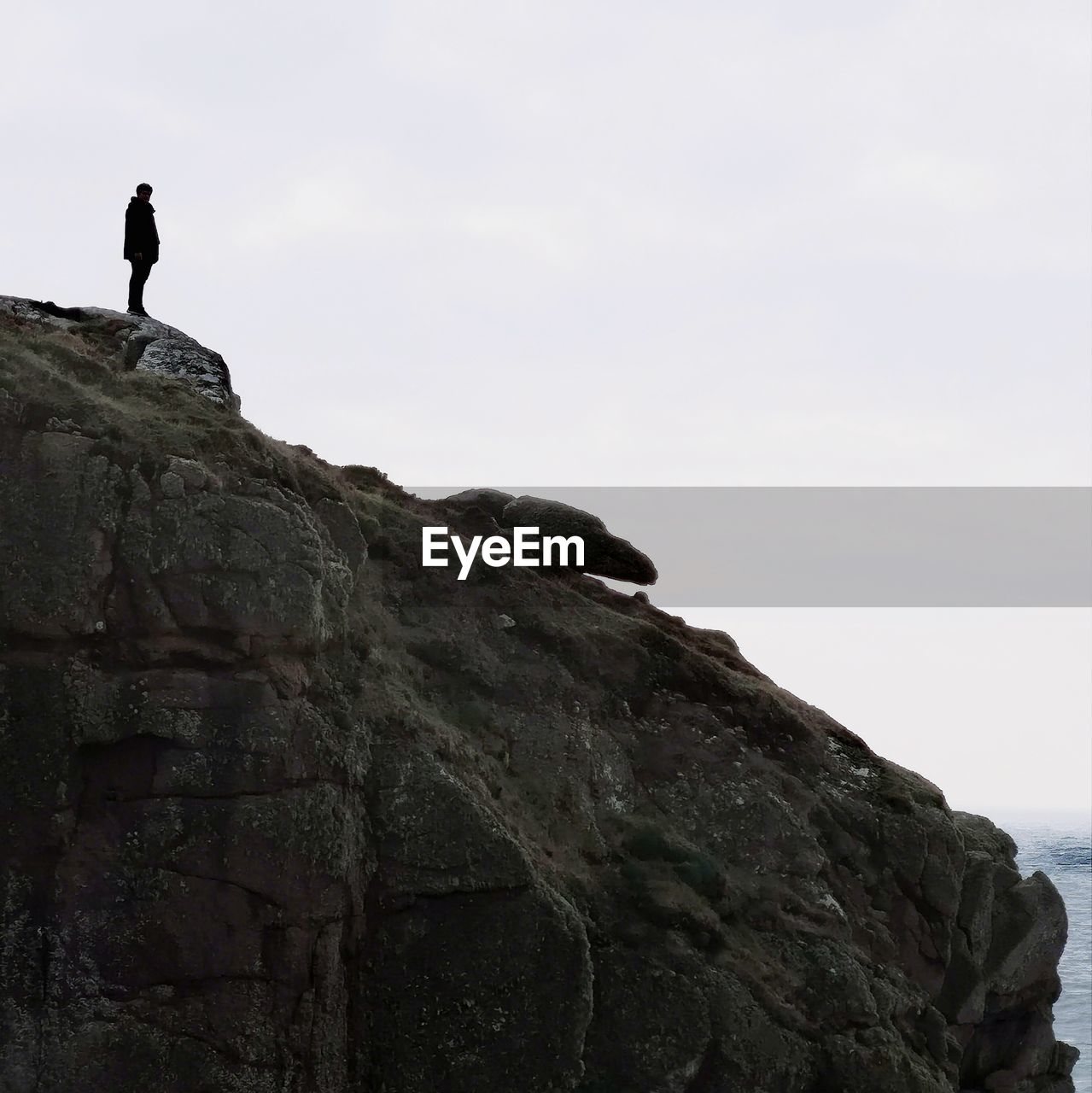 Low angle view of man standing on rock against sky
