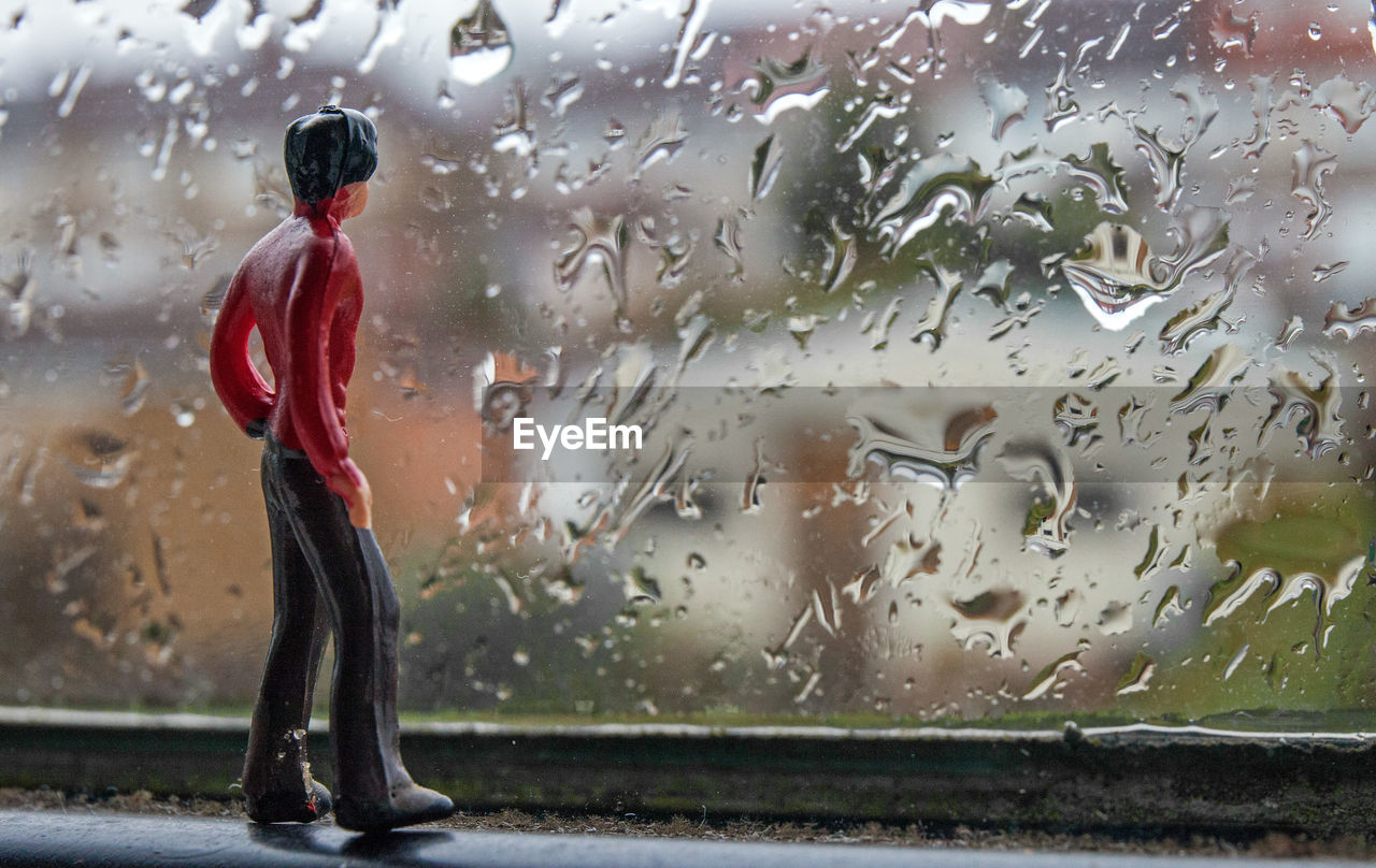 WOMAN STANDING ON WET GLASS WINDOW