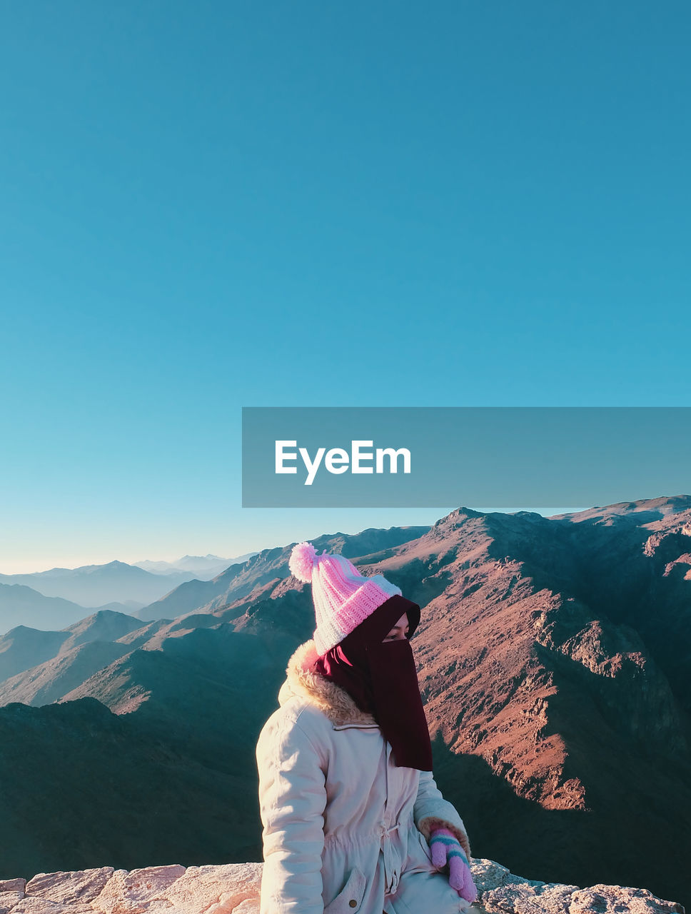 Rear view of woman looking at mountain against clear sky