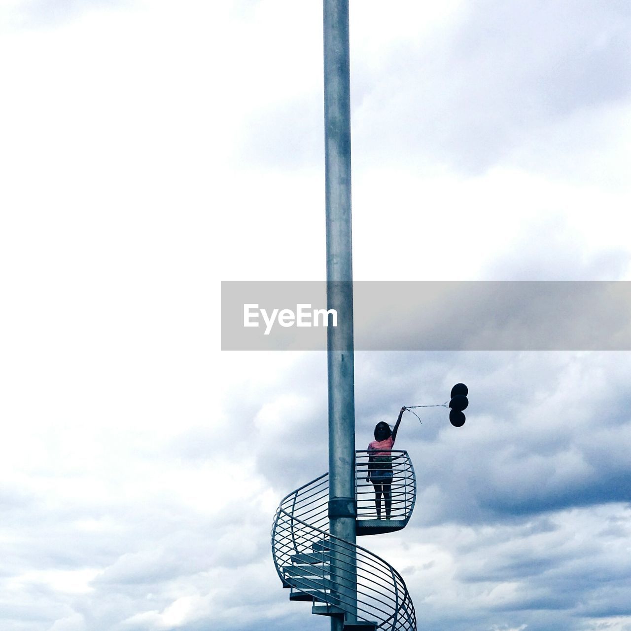 Rear view of woman on stairs against clouds