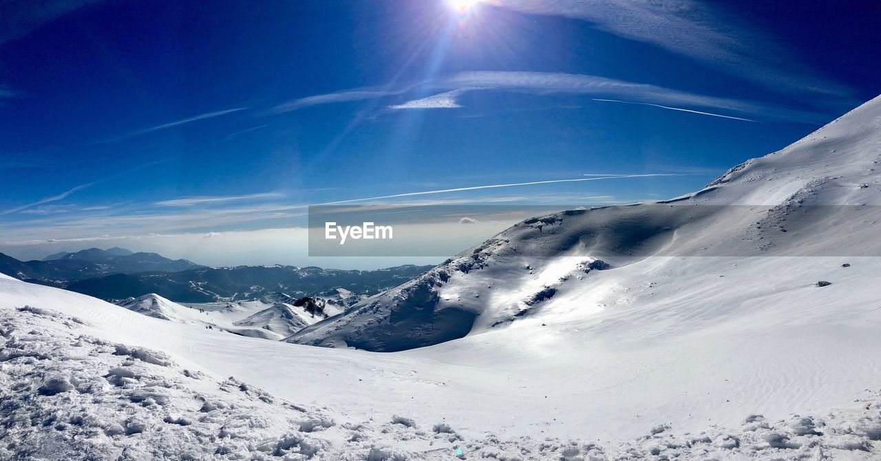 Scenic view of snowcapped mountains against blue sky