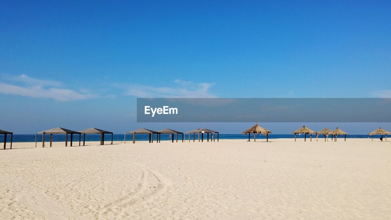 Gazebos on sea shore at beach against sky