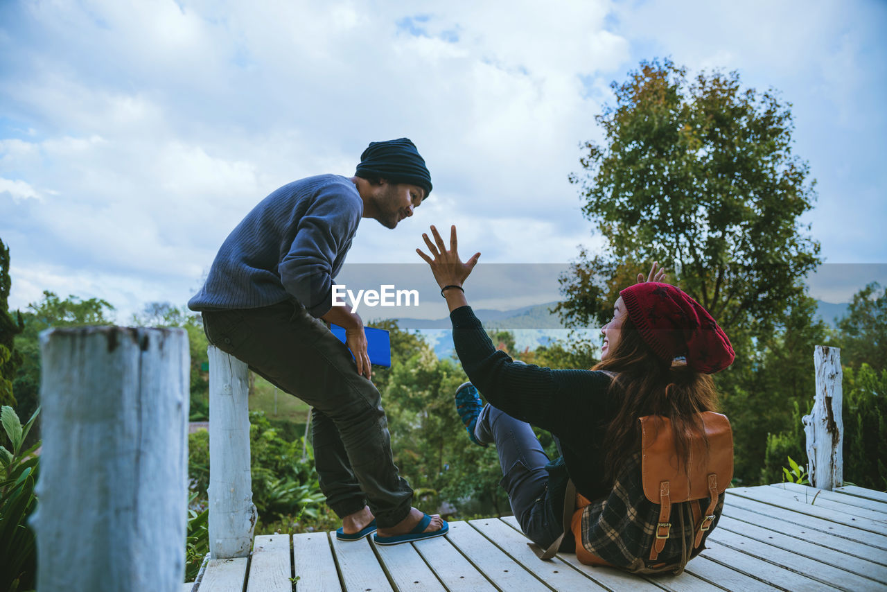 SIDE VIEW OF PEOPLE SITTING ON PLANTS