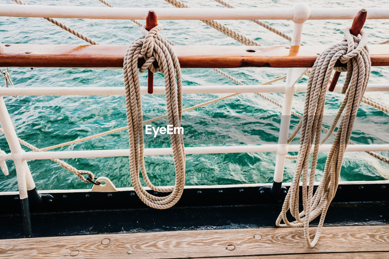 Close-up of rope tied to bollard on railing