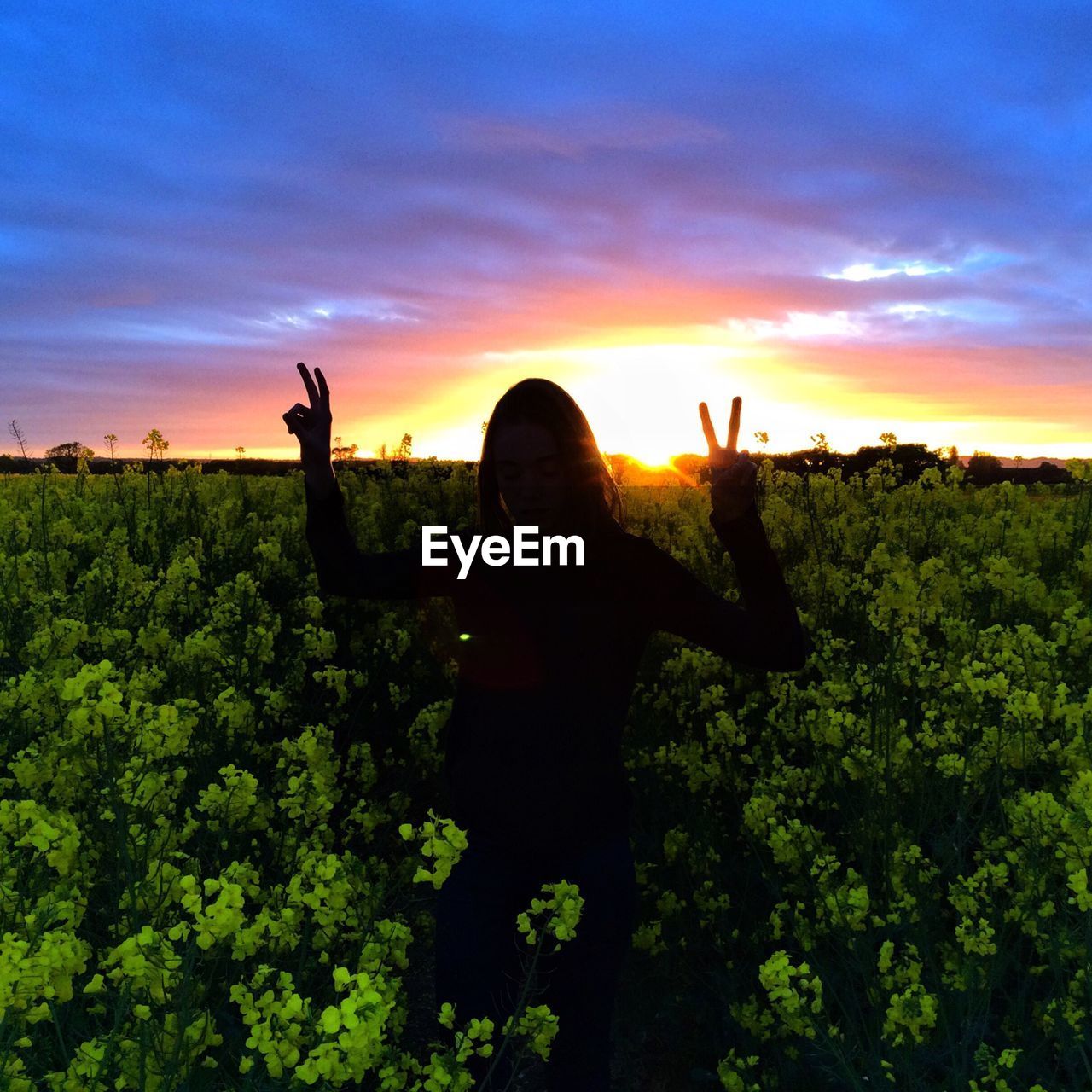 Woman standing in field against dramatic sky