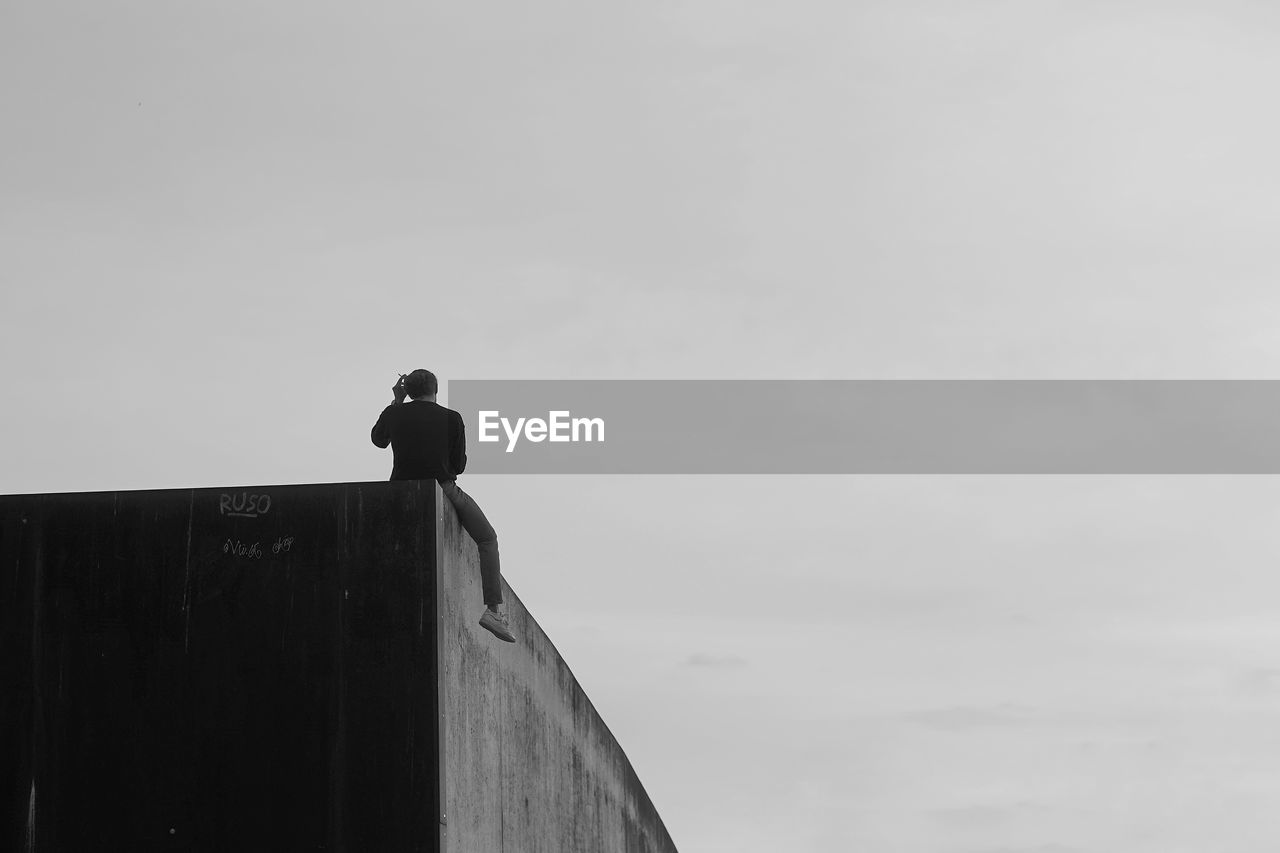 LOW ANGLE VIEW OF BIRD PERCHING ON A BUILDING