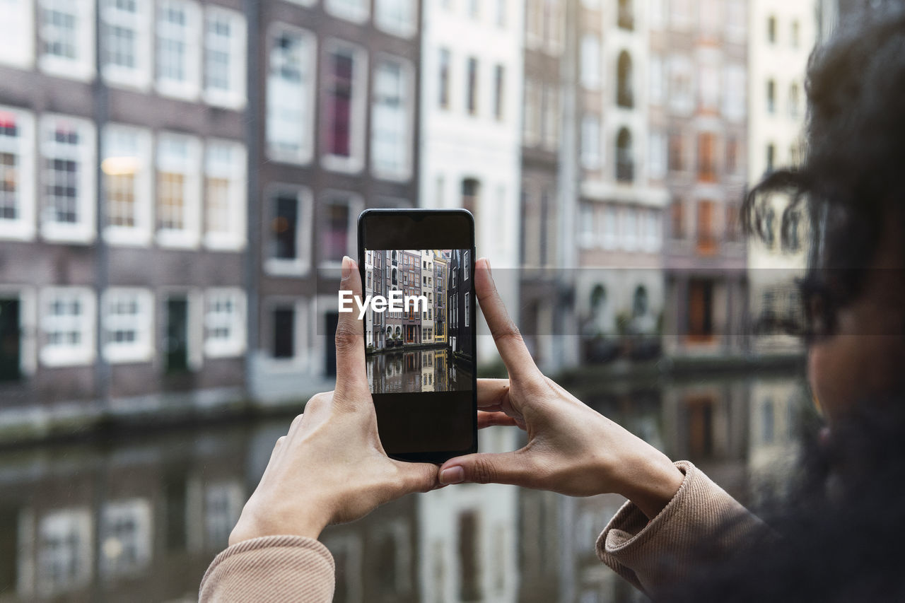 Young woman photographing city through smart phone