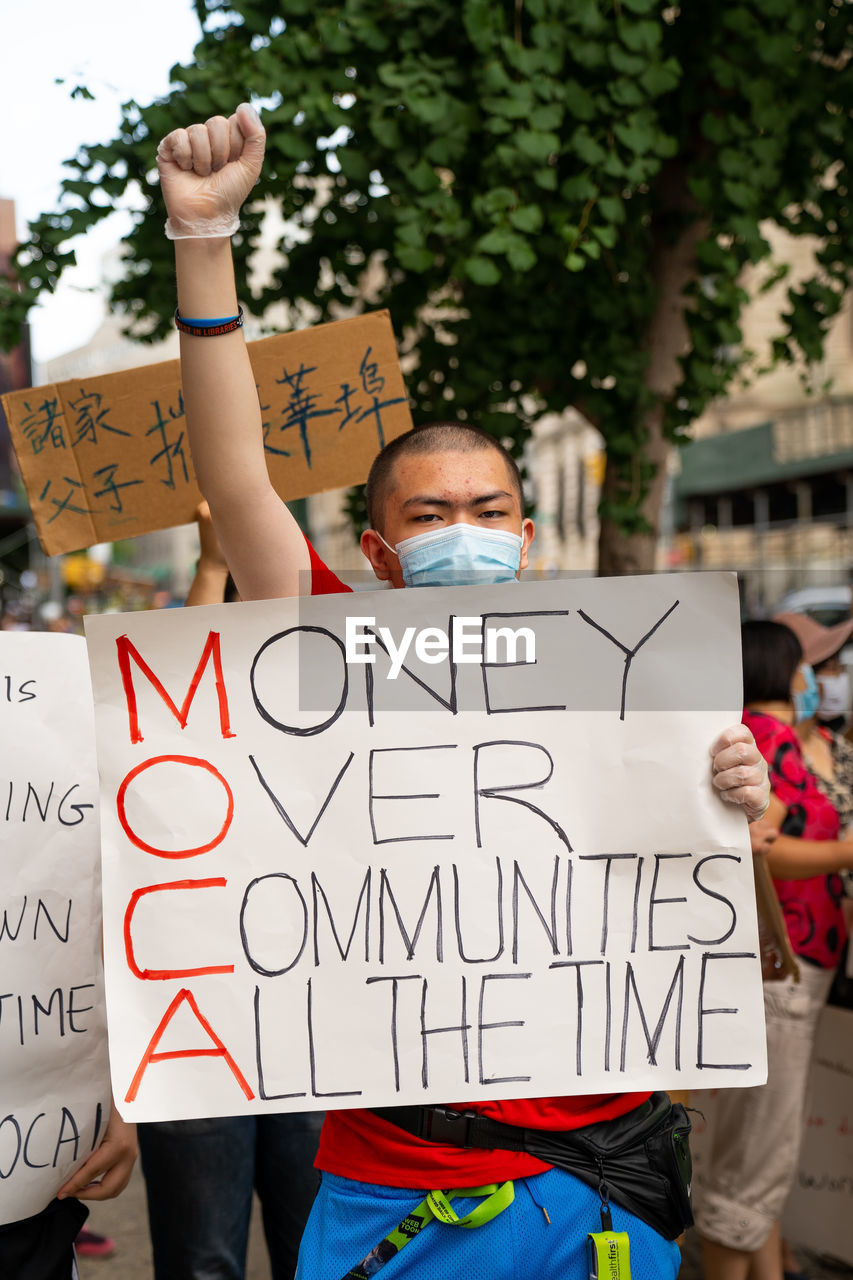 LOW SECTION OF MAN HOLDING TEXT ON SIGN