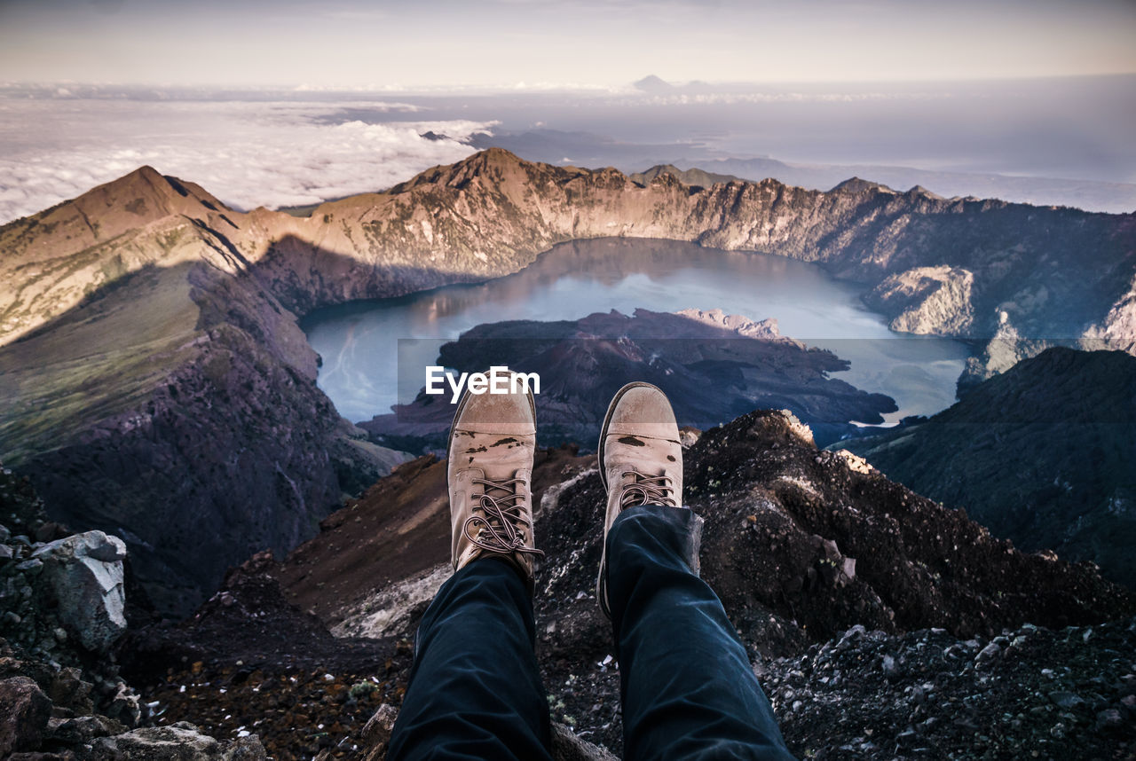 Low section of person relaxing on mountain by lake