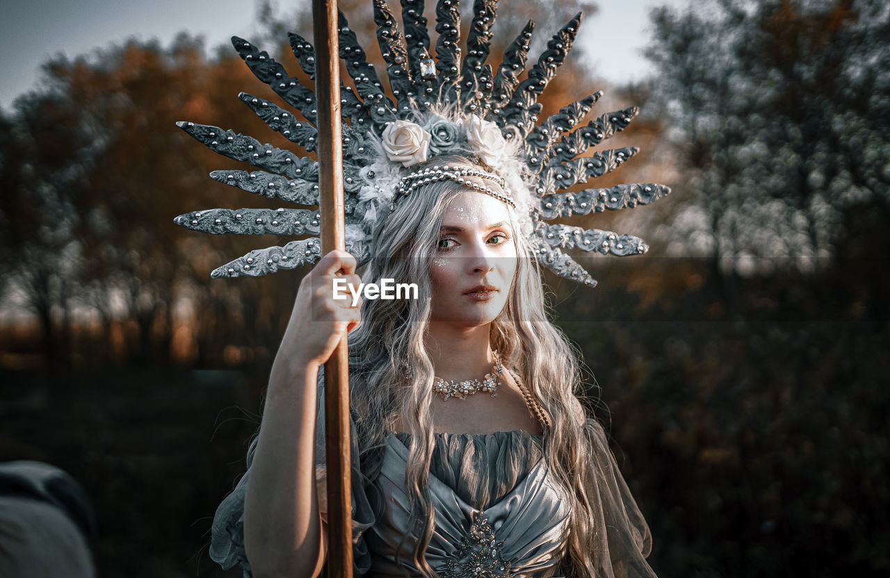 Young woman wearing costume standing against tree