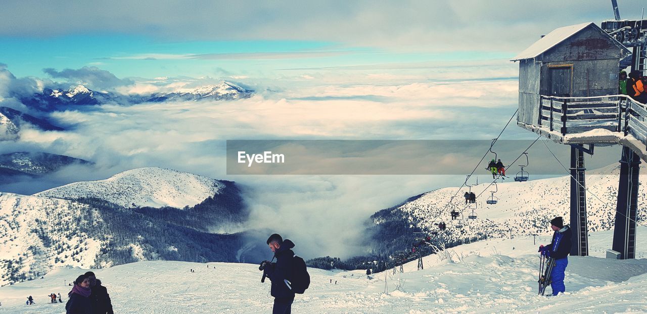 PEOPLE STANDING ON SNOW AGAINST SKY