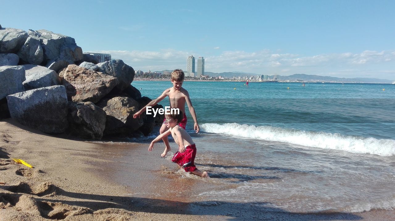 Siblings playing on shore at beach