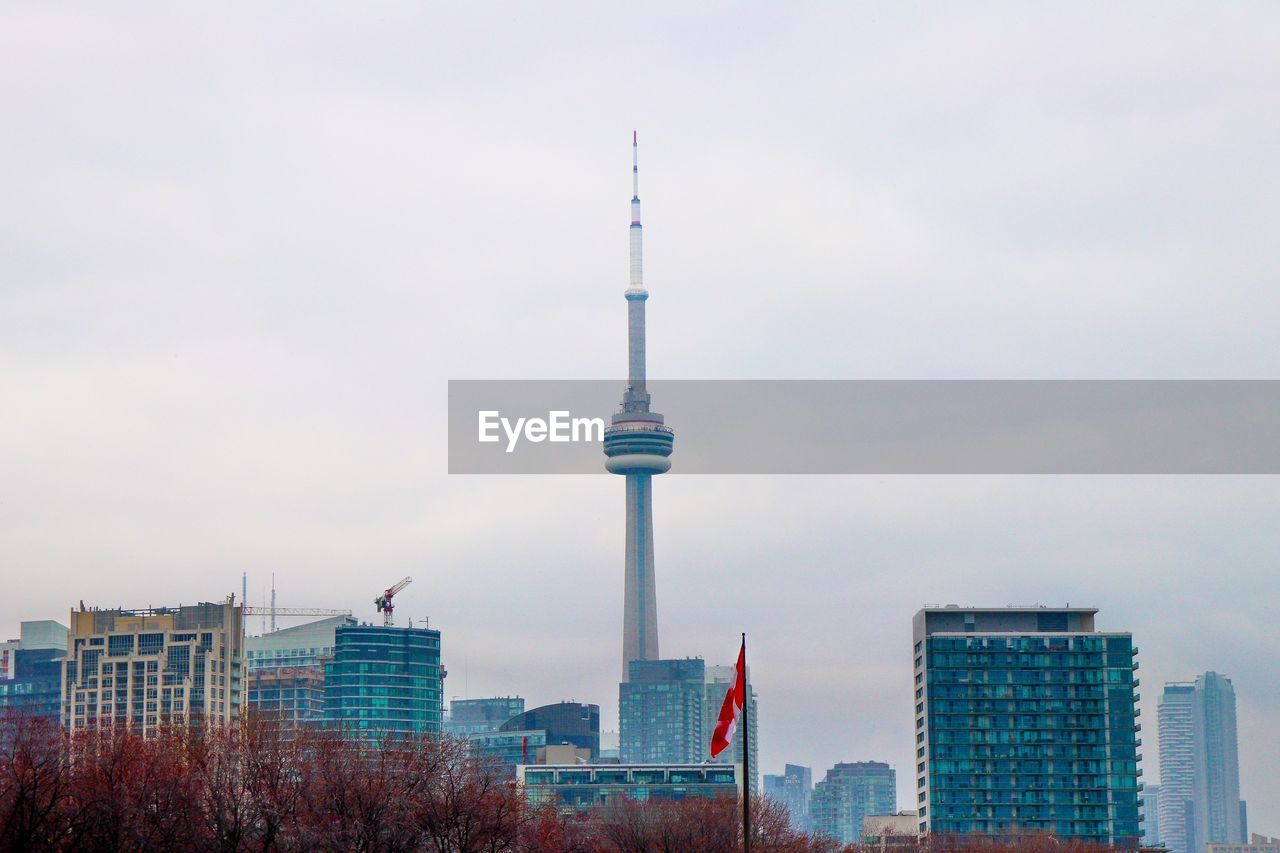 Cn tower by modern buildings in city against sky