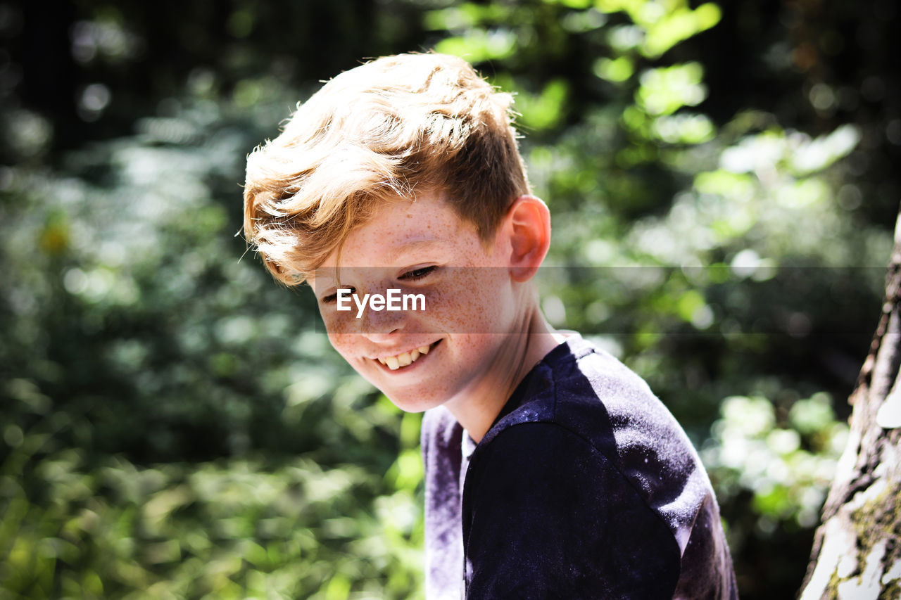 Smiling boy looking down in sunny day