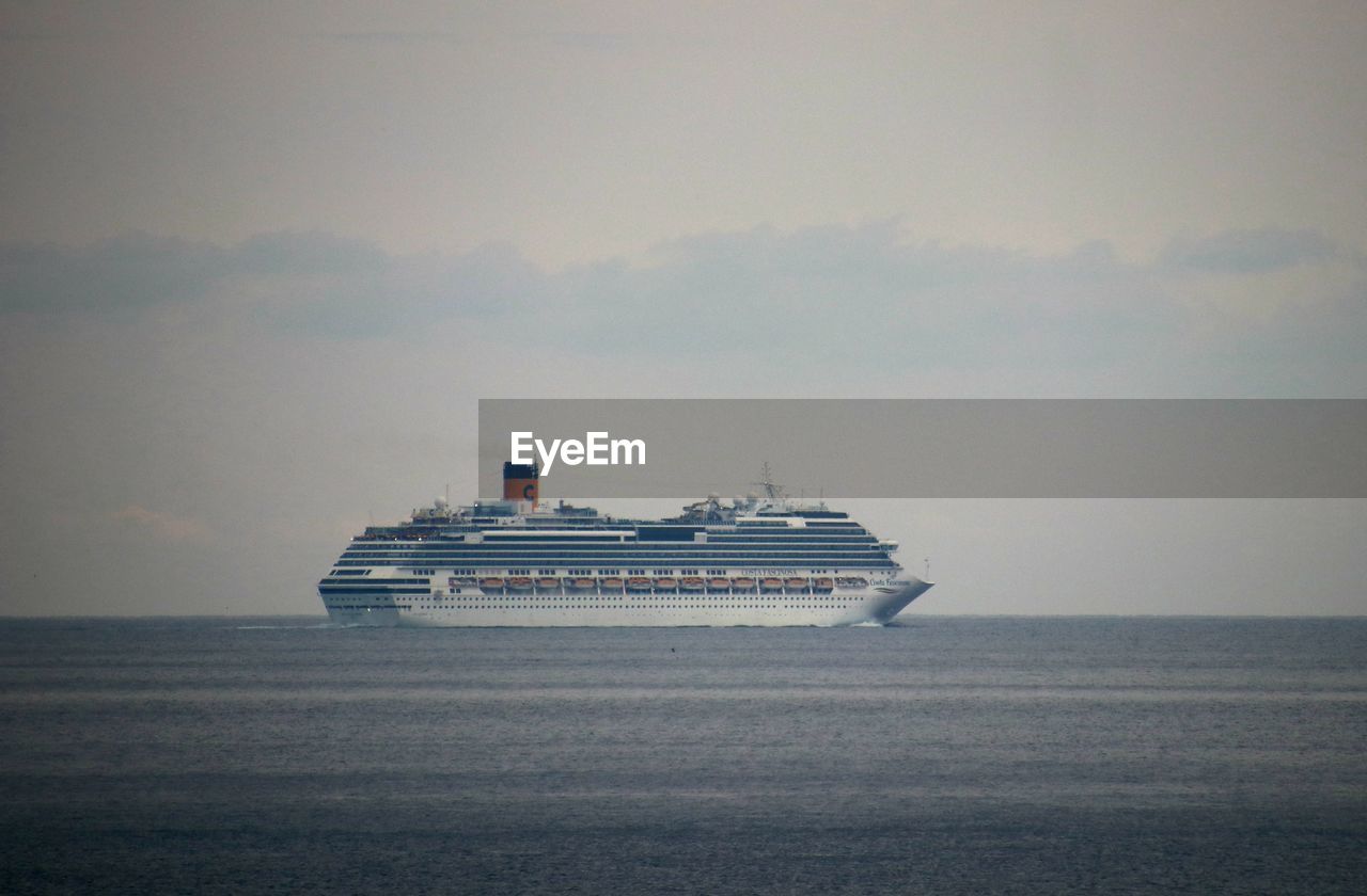 BOAT SAILING IN SEA AGAINST SKY