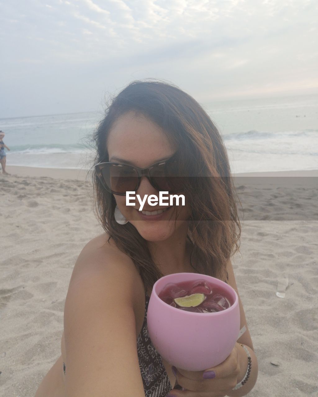 PORTRAIT OF SMILING YOUNG WOMAN ON SUNGLASSES AT BEACH