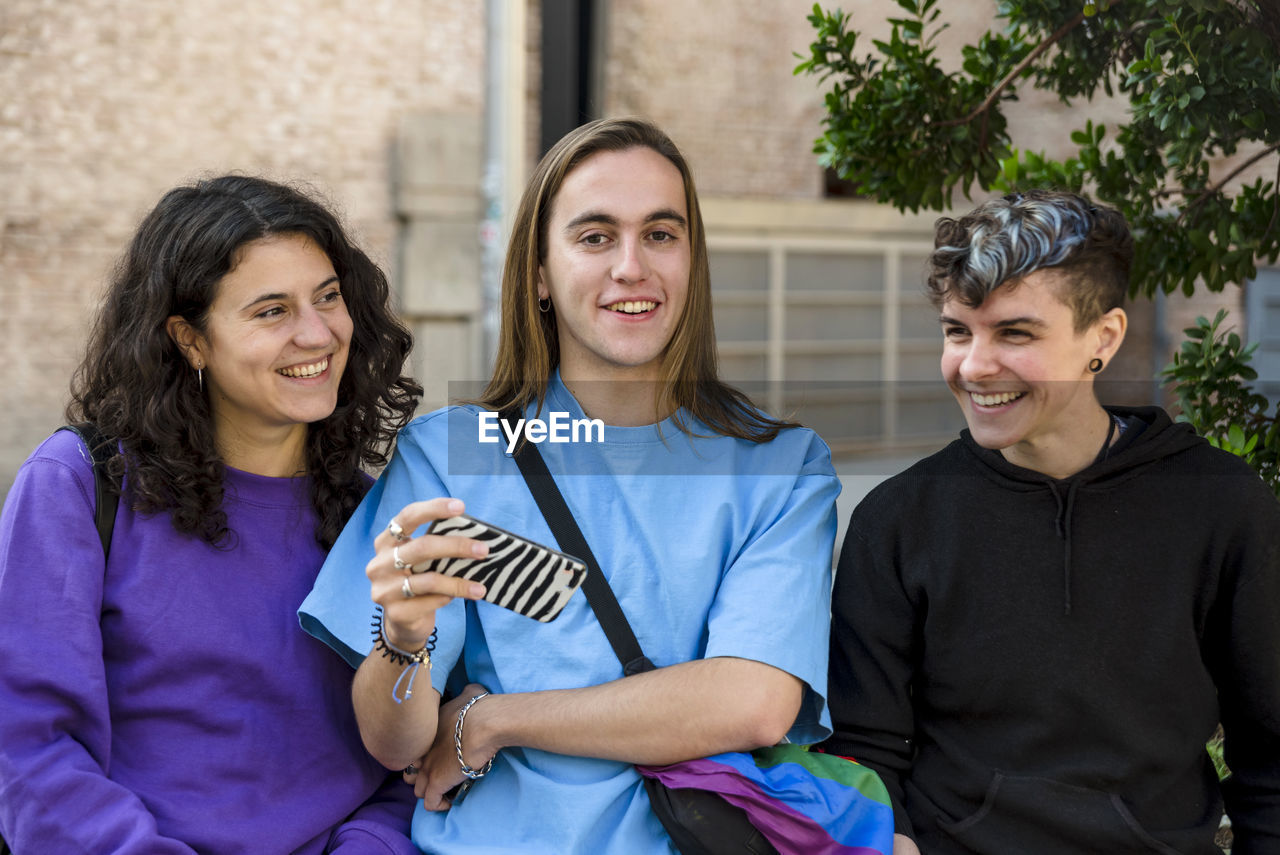 Young diverse friends taking selfie with a mobile phone outdoors.