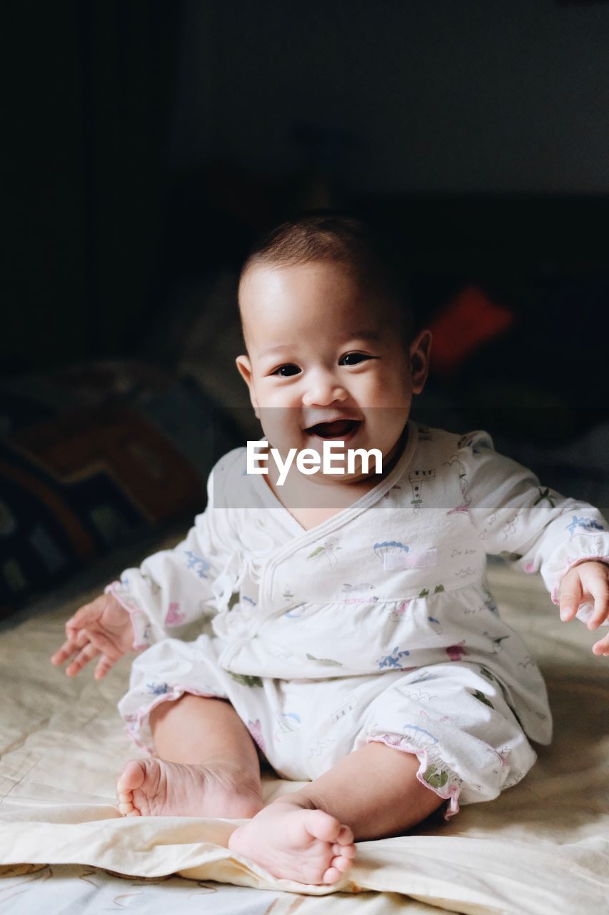 Portrait of smiling cute baby girl sitting at home