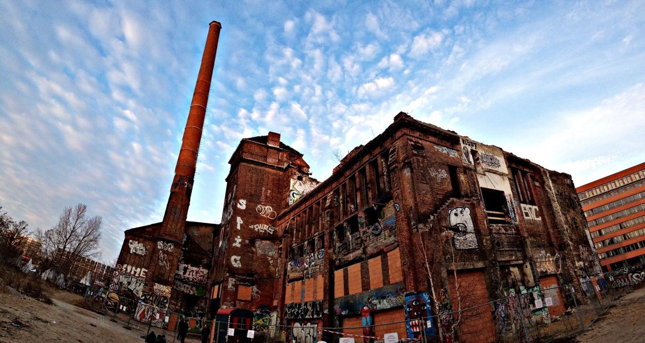 Low angle view of graffiti on building against cloudy sky