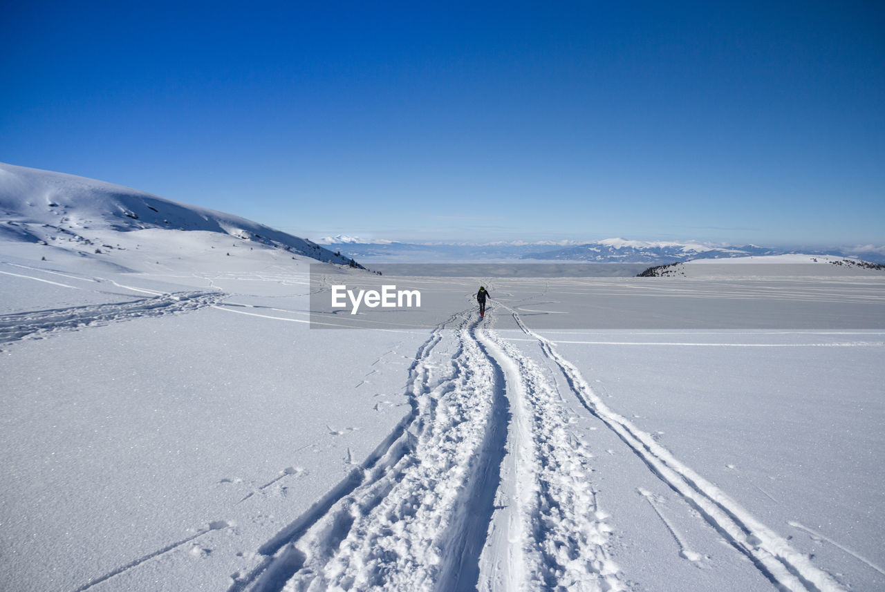 Person on snow covered field against sky