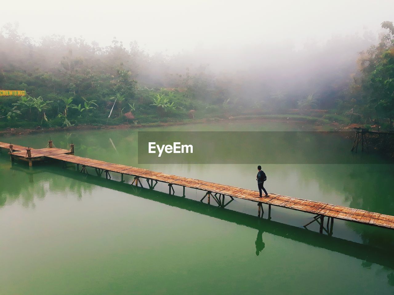 Person walking on footbridge over lake