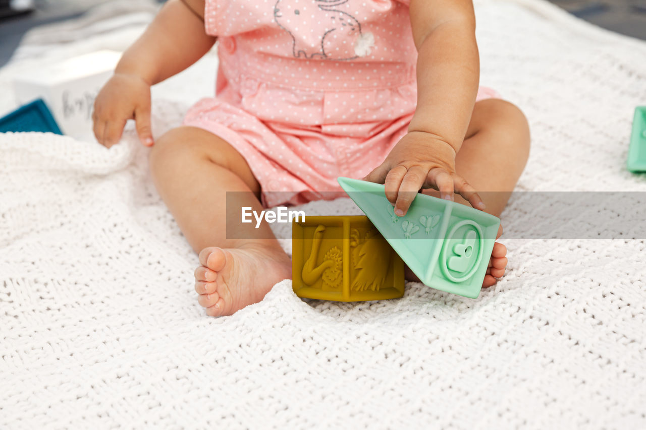 MIDSECTION OF WOMAN HOLDING TOY WHILE SITTING AT HOME