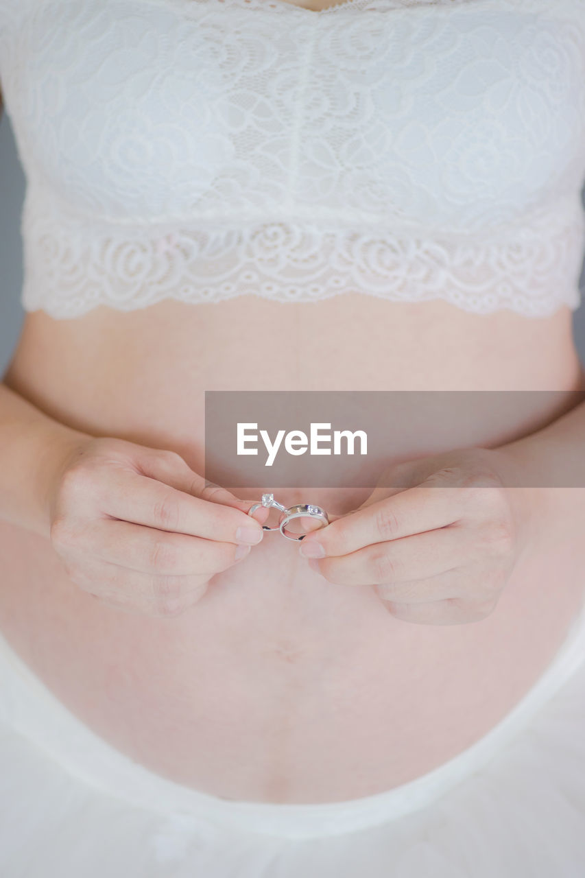 Midsection of pregnant woman holding rings