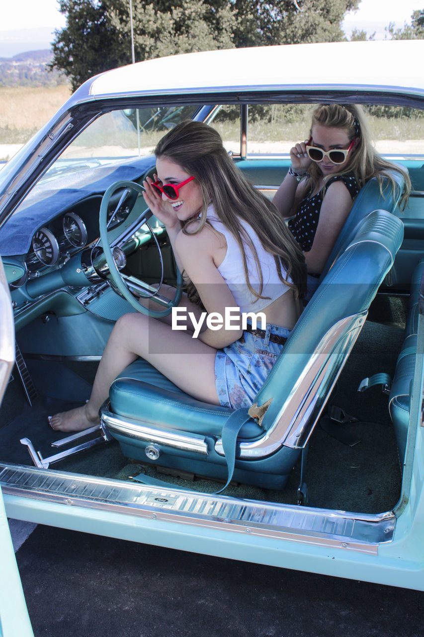 Smiling young friends sitting car