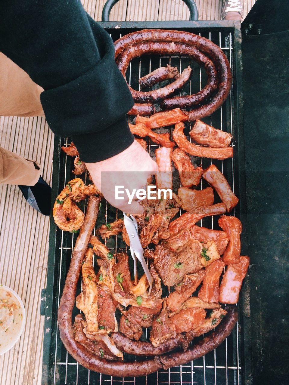 Low section of man cooking meat on barbecue grill