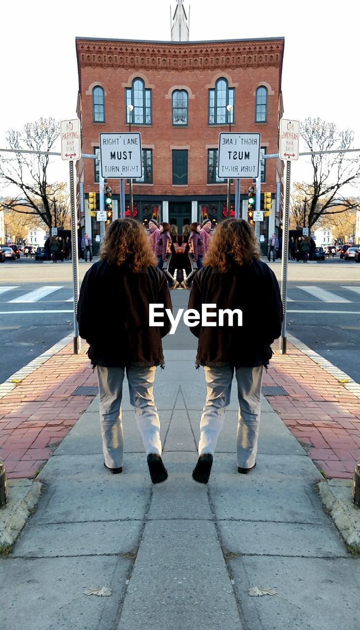 REAR VIEW OF WOMAN WALKING ON SIDEWALK