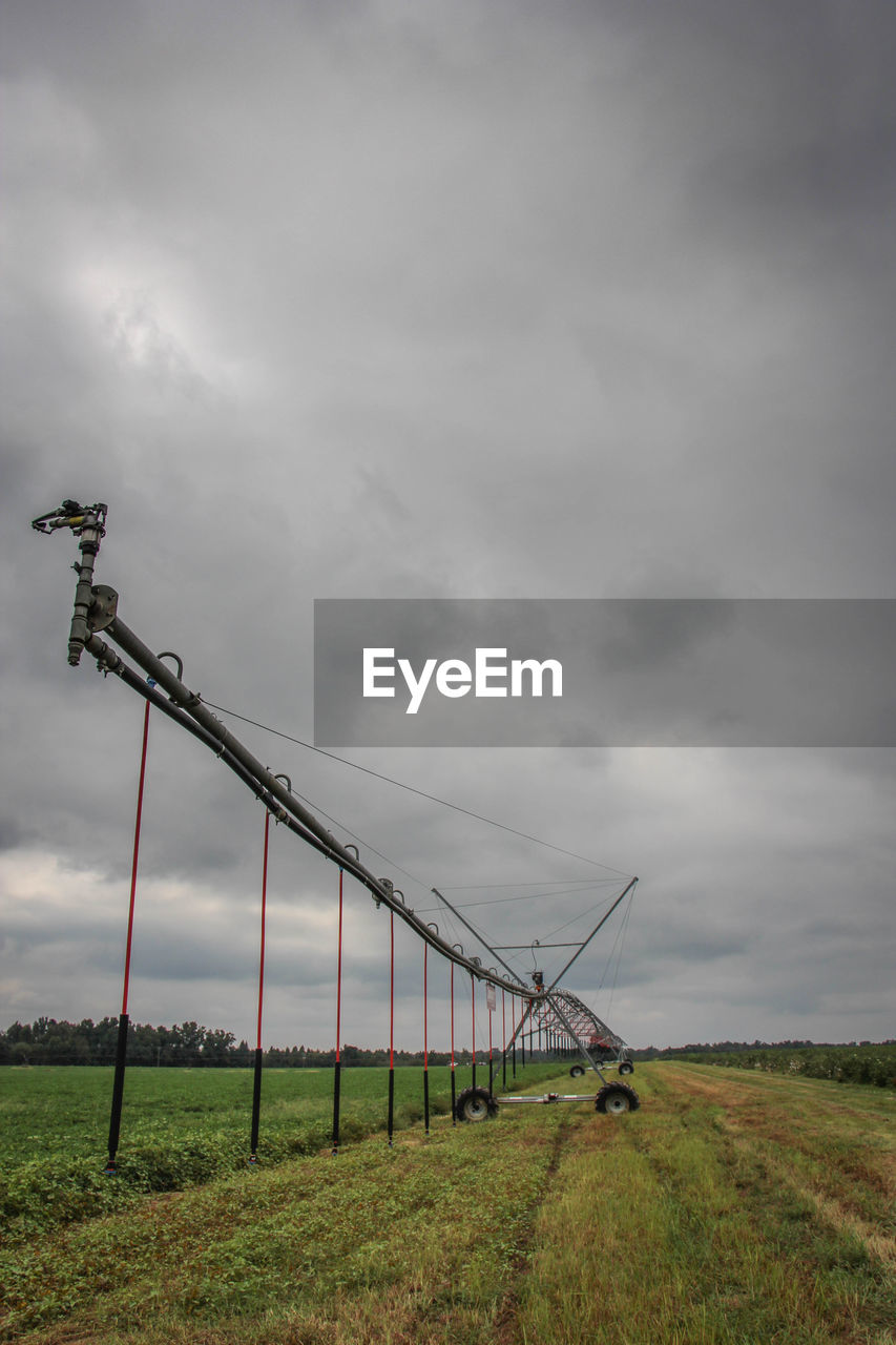 Crane on field against storm clouds