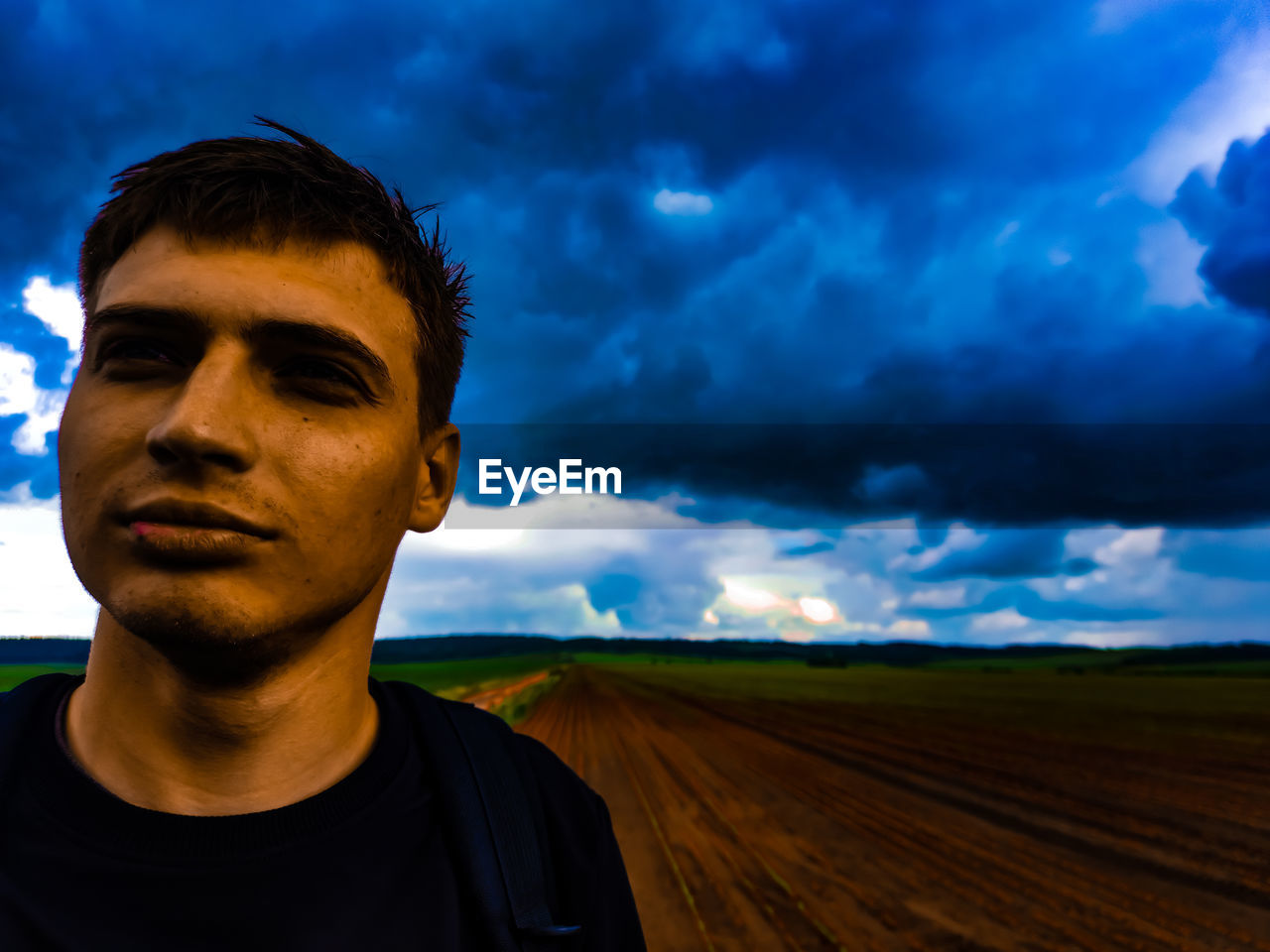 PORTRAIT OF YOUNG MAN LOOKING AT FIELD