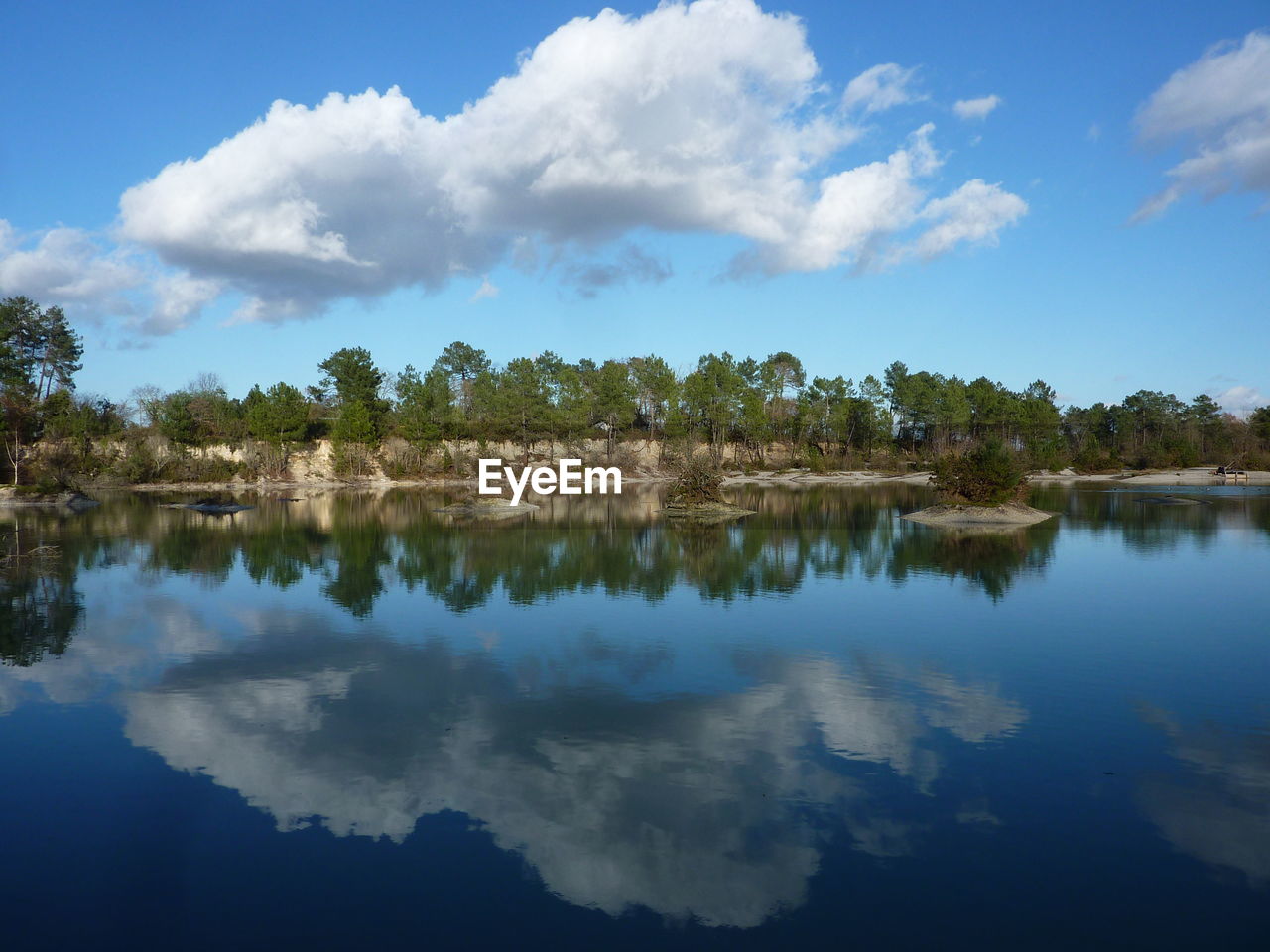 SCENIC VIEW OF CALM LAKE AGAINST CLOUDY SKY