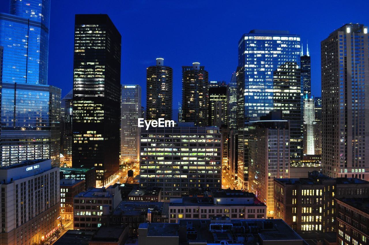 Illuminated buildings in city against sky at night