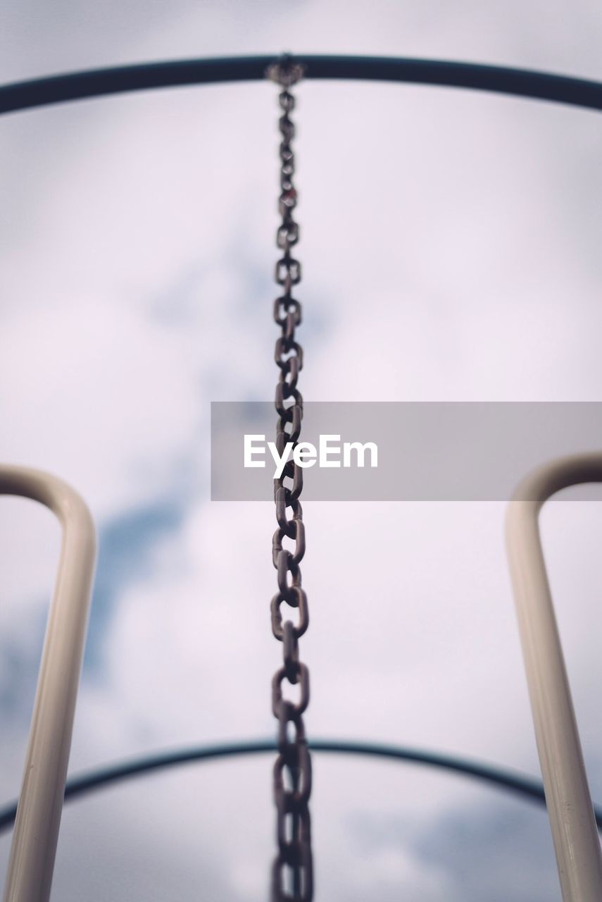 Low angle view of metallic chain hanging on outdoor play equipment at playground