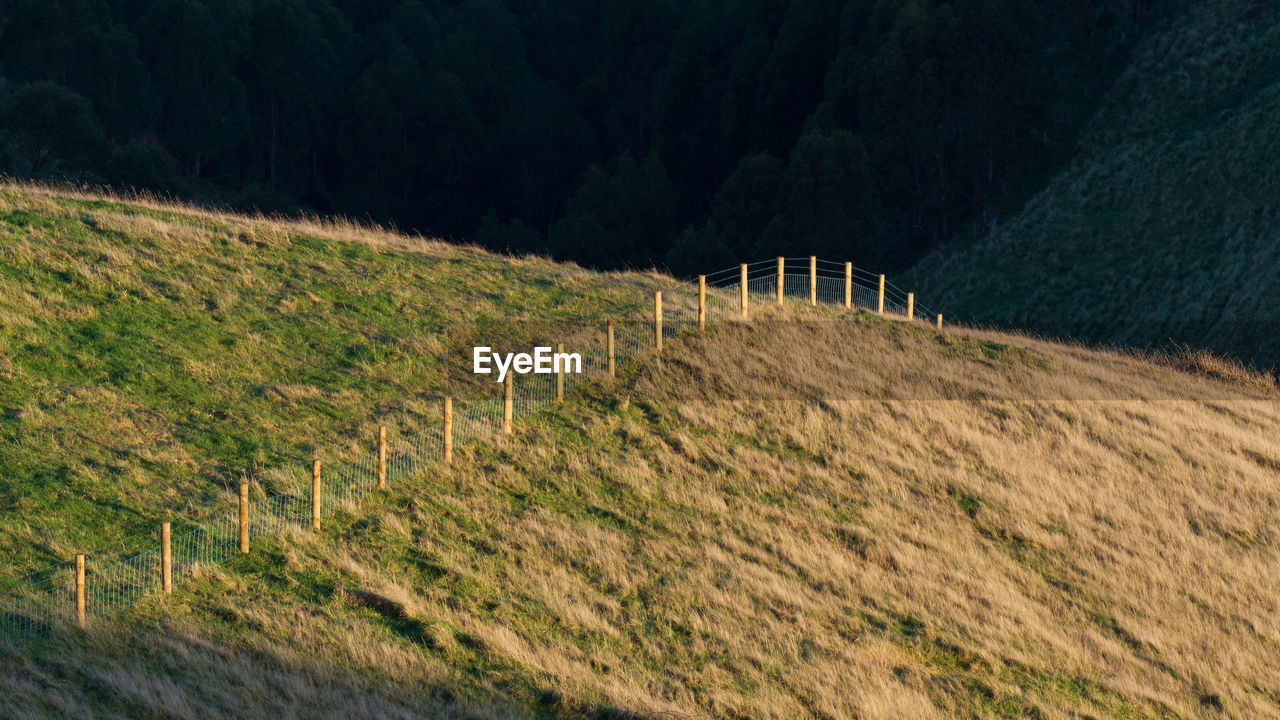 Scenic view of a fence line over a field against mountain