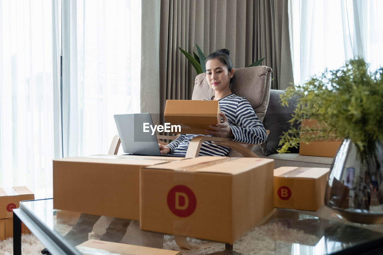 side view of woman using digital tablet while sitting on sofa