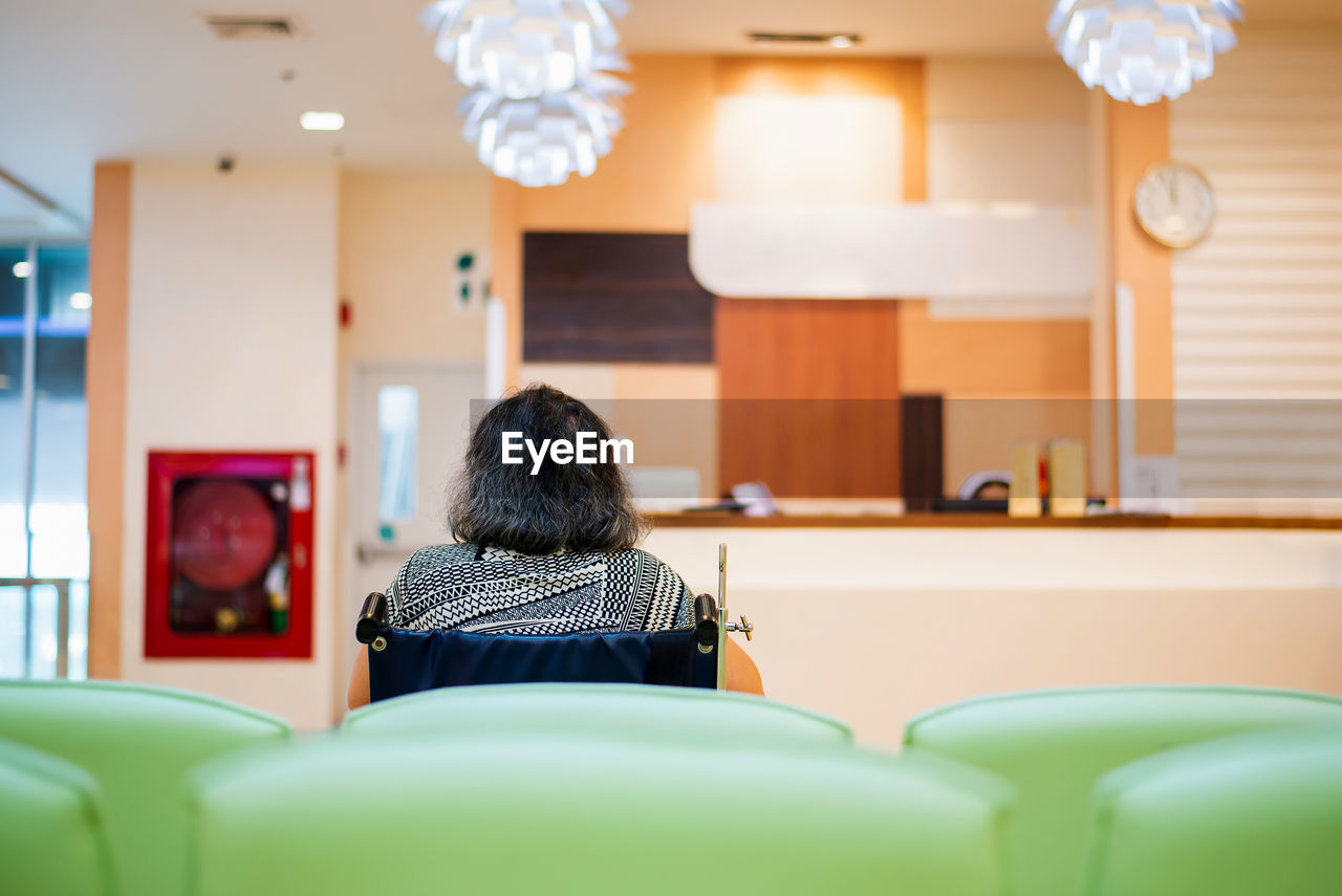 Rear view of disabled woman sitting on wheelchair