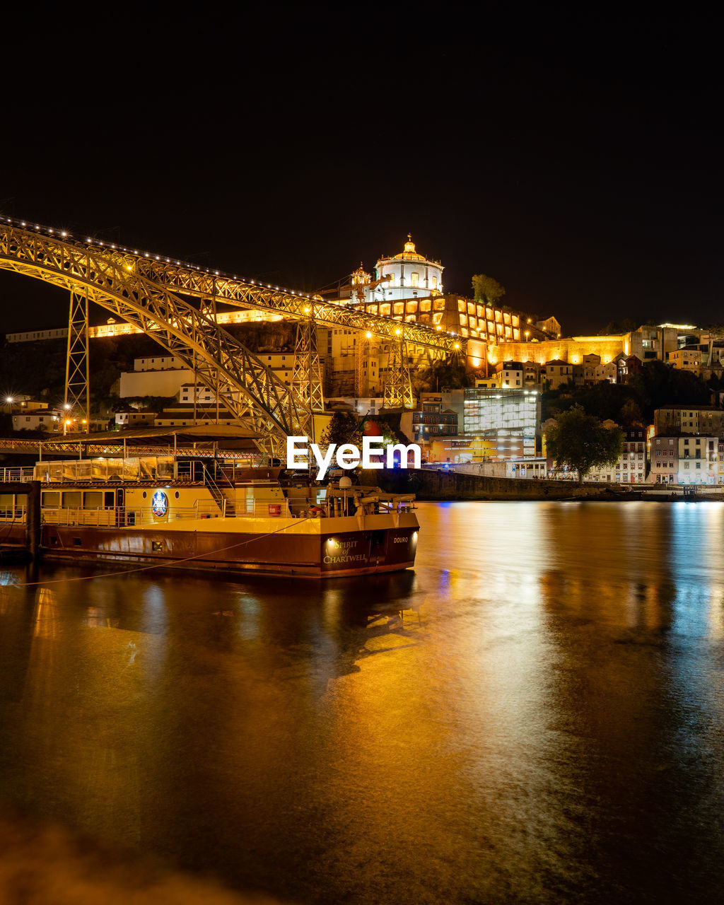 ILLUMINATED BUILDINGS BY RIVER AT NIGHT