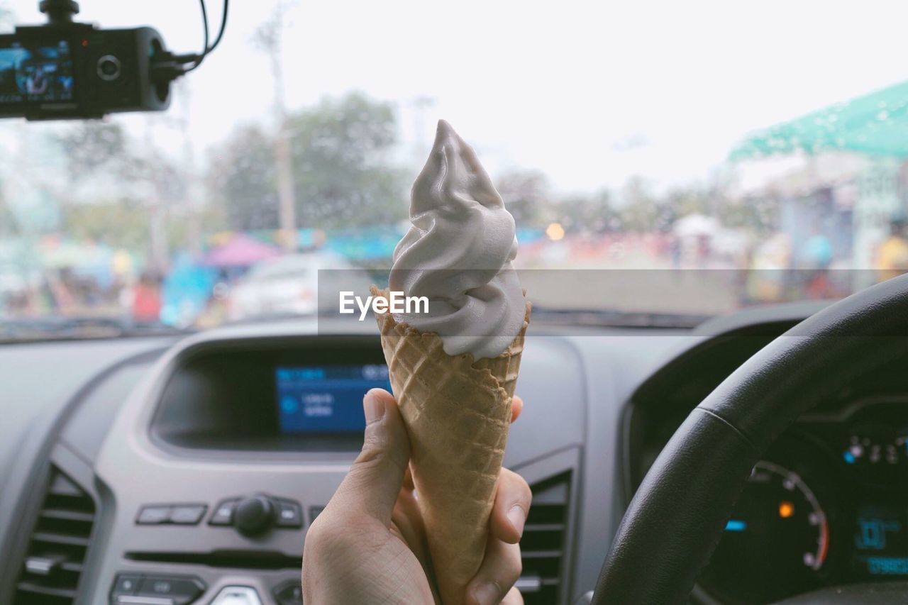 Close-up of person holding ice cream in car