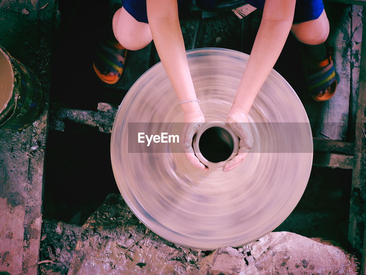 Low section of woman shaping earthenware on pottery wheel