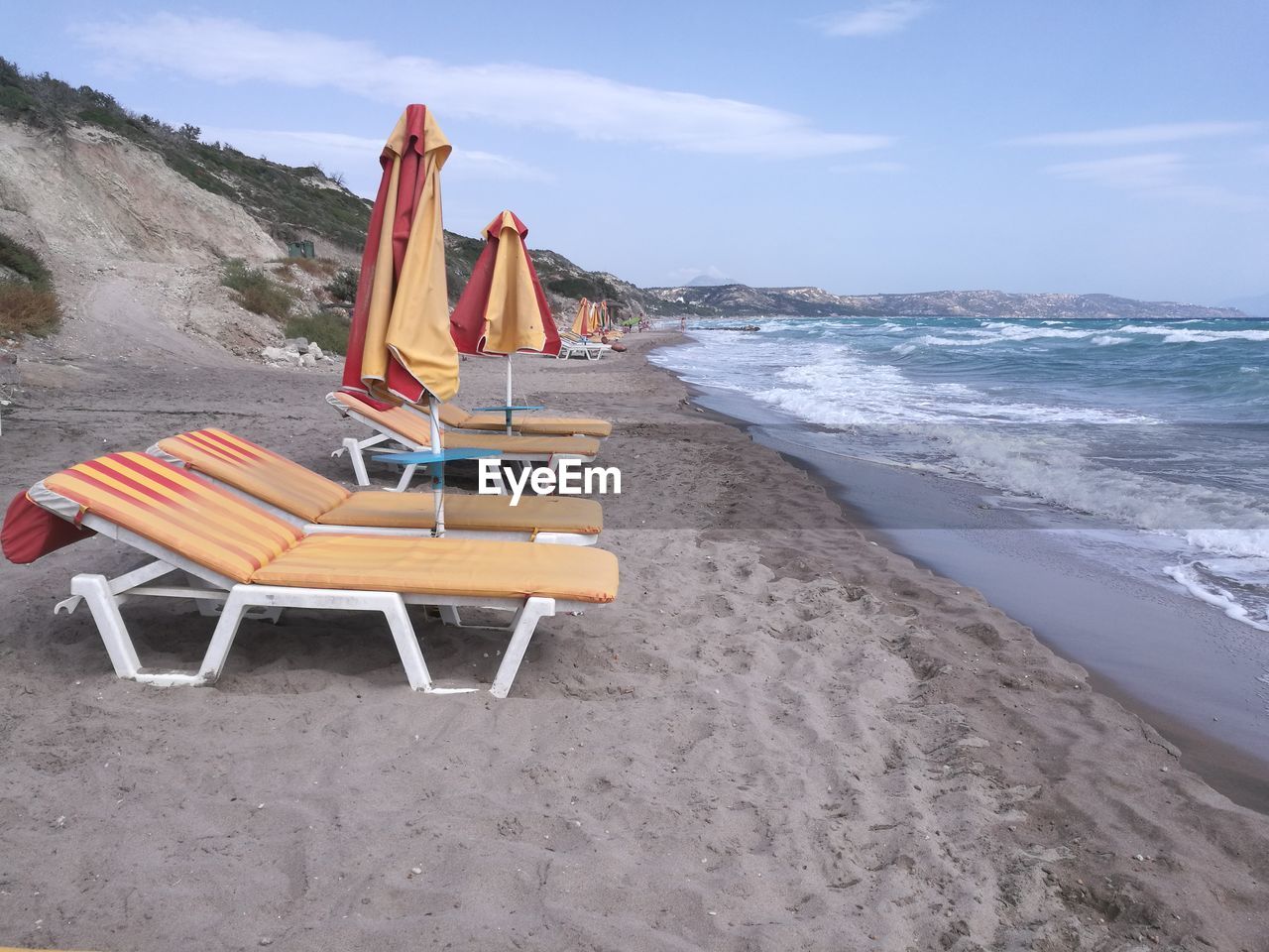 DECK CHAIRS ON BEACH AGAINST SKY