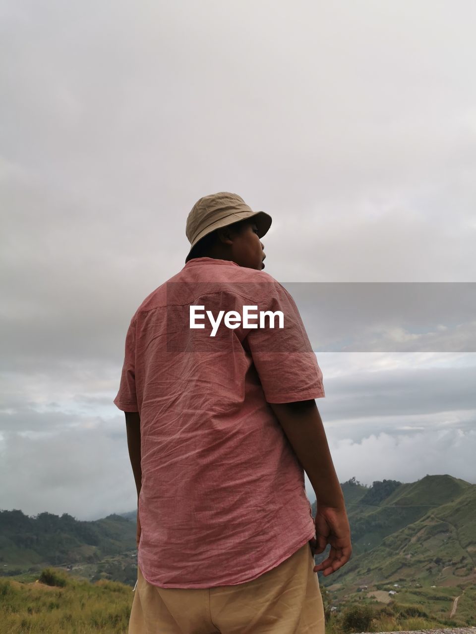 Rear view of man standing on mountain against sky