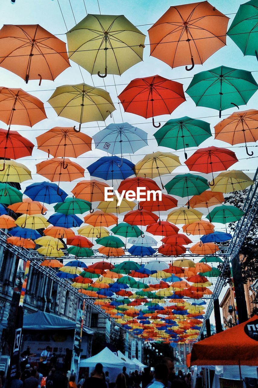 LOW ANGLE VIEW OF MULTI COLORED UMBRELLAS HANGING AT MARKET