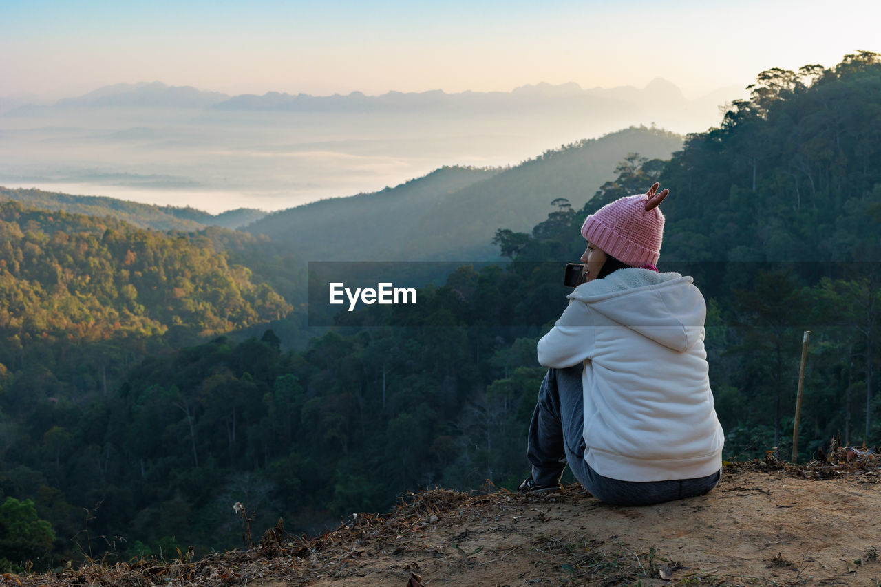 rear view of woman standing on mountain against sky