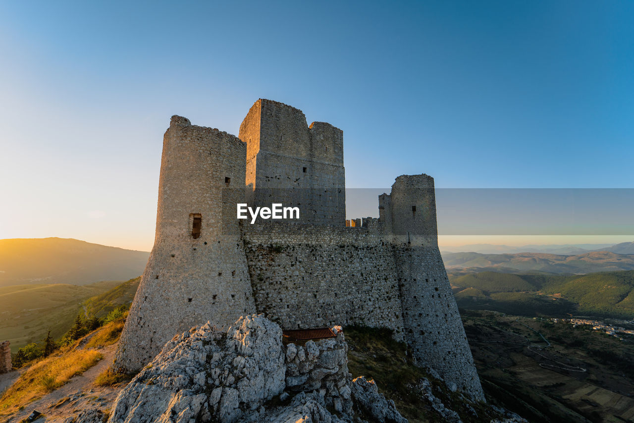 Castle on mountain against blue sky