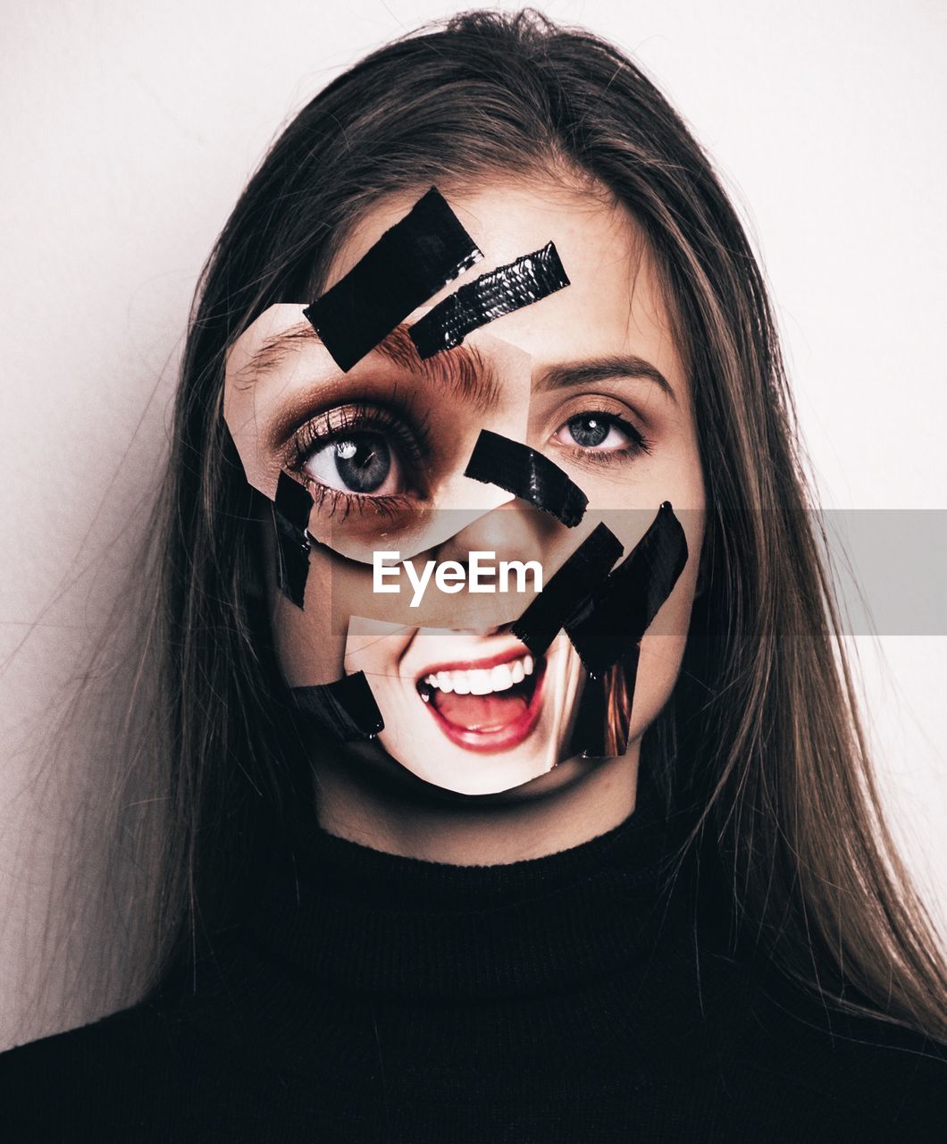 Close-up portrait of sad young woman with adhesive tape and photographs against wall