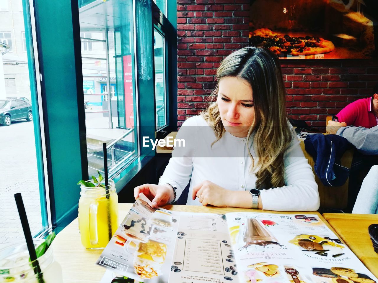 Young woman reading menu at restaurant