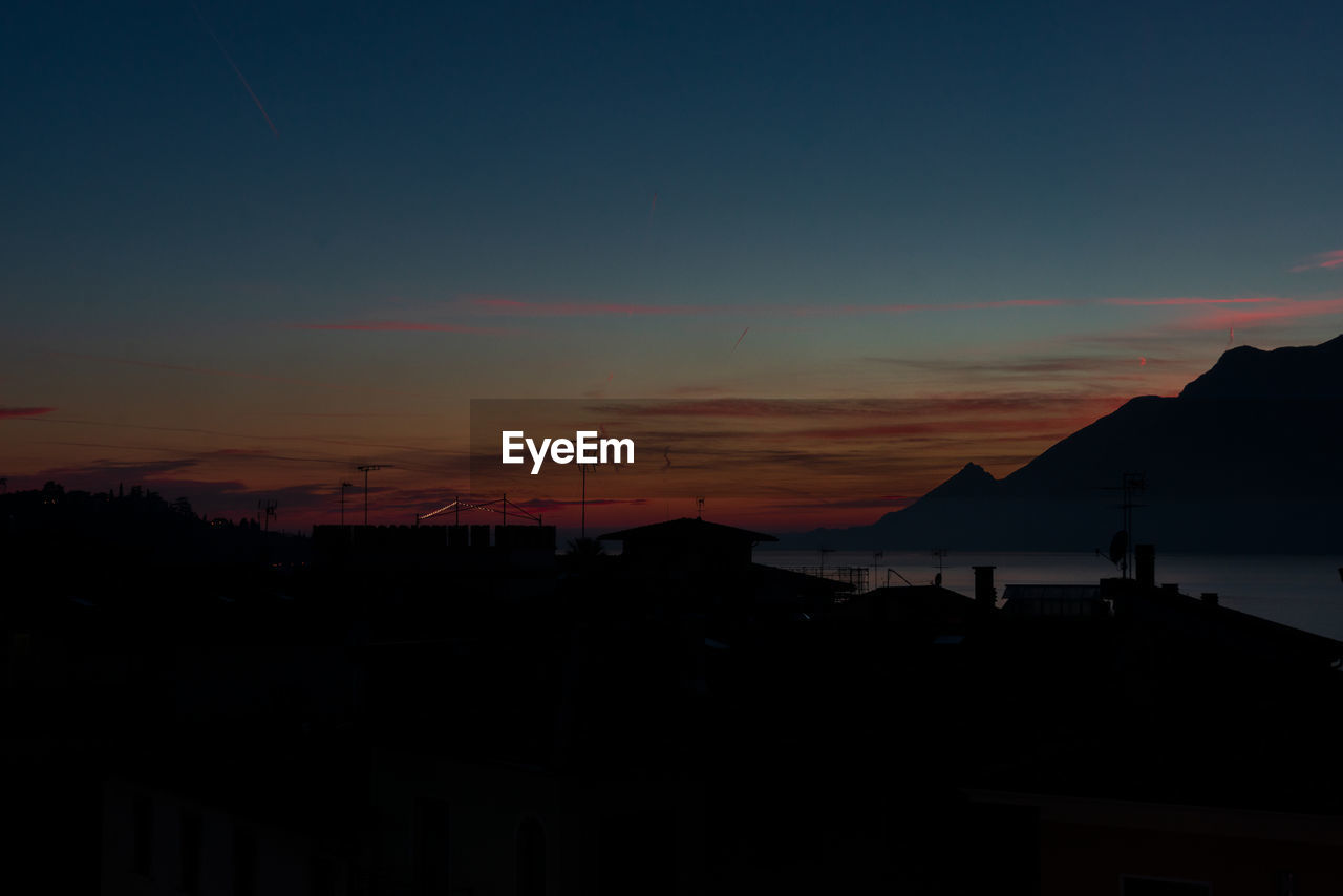 Silhouette buildings against sky at sunset